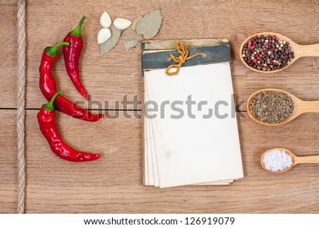 Old recipe book, red chili pepper, spices, garlic, bay leaf on oak wood texture background