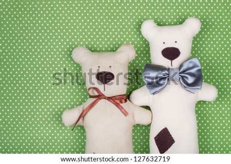 Handmade toy bears pair on green cotton background
