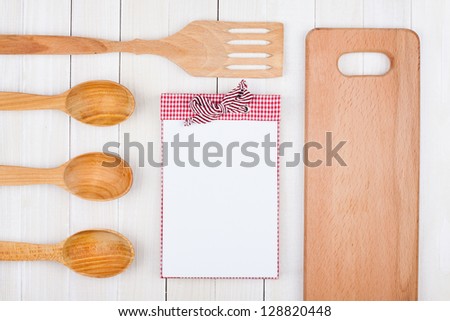 Recipe notebook, kitchen equipment on white wood background