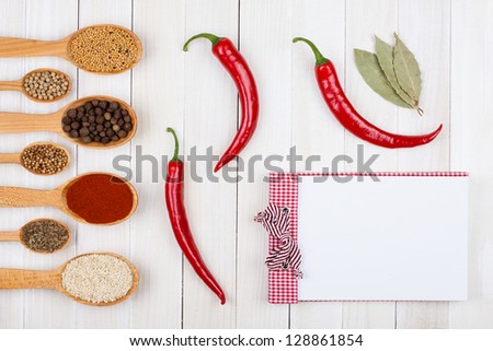 Recipe cook book, spices in wooden spoons on white wood background