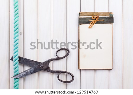 Notebook, old scissors, rope on white wood background