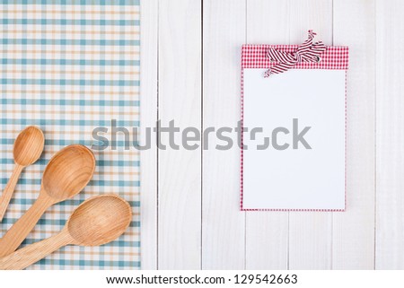 Recipe book, kitchen equipment on white wood background