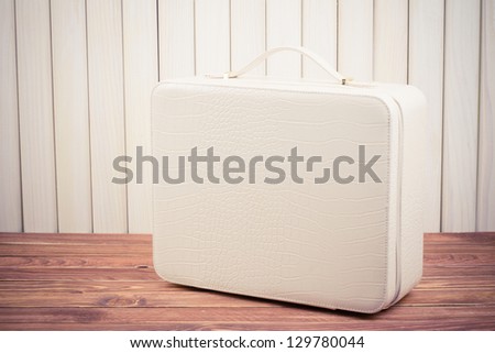 White leather travel suitcase on wood vintage photo