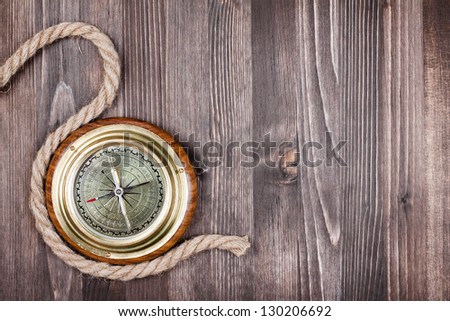 Big vintage compass and rope on wooden texture background