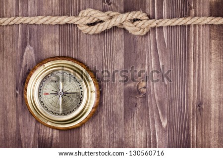 Big vintage compass and rope on wooden texture background