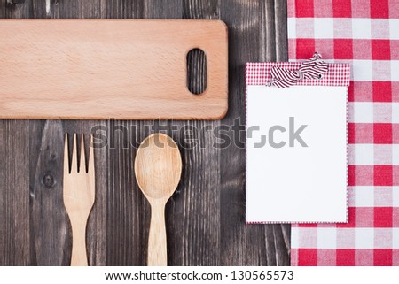 Cook recipe book, tablecloth, kitchen equipment on wood background