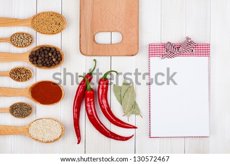 Cook book, spices in wooden spoons on white wood background