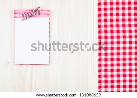 Recipe notebook, red and white tablecloth on wood background