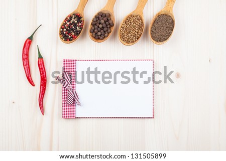 Cook book, spices in spoons, chili on white wood background