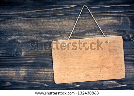 Wooden signboard with rope hanging on planks background