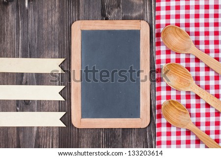 Kitchen tablecloth, menu board, spoons, labels on wood background