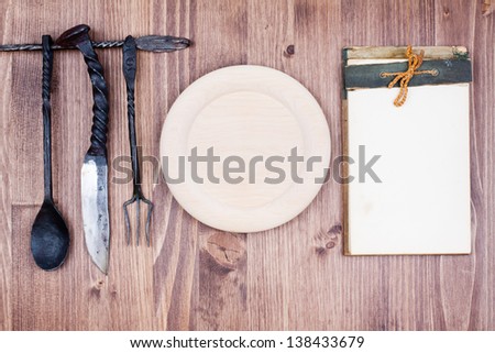 Cook book, wooden plate, spoon, fork, knife on wood background