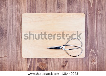 Scissors and sign board on wood textured background