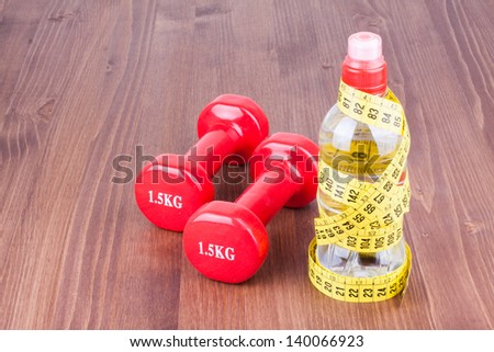 Fitness sport dumbbells,measure tape, bottle of water on wood floor