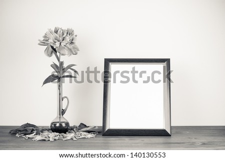 Peony flower in glass vase and photo frame on wooden table