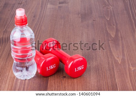 Fitness sport dumbbells,bottle of water on wood floor