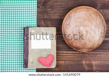 Old cook book with heart, tablecloth, plate on wooden table background
