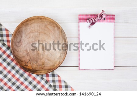 Recipe cook book, wood plate, tablecloth on white wood background