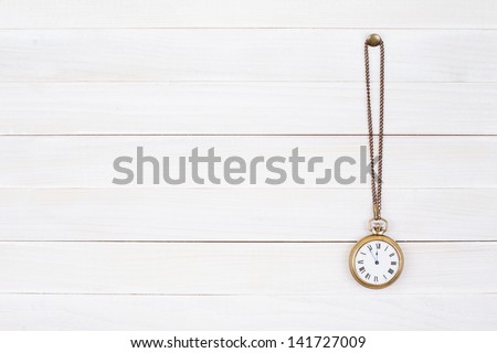 Vintage bronze pocket watch on white wood wall background