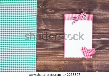 Cook book with heart, tablecloth on wooden table background