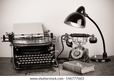 Vintage typewriter, old telephone, desk lamp, book sepia photo