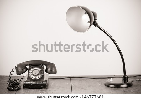 Retro telephone and old table lamp on table sepia photo