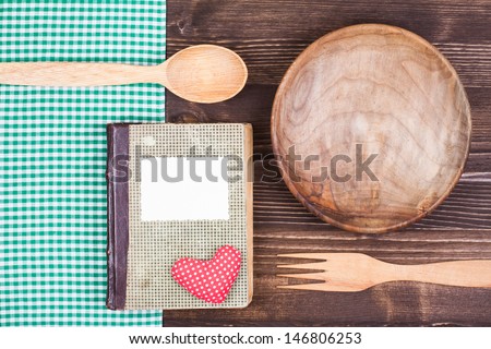 Old cook book, tablecloth, spoon, fork, heart on wood background