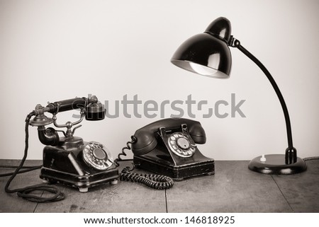 Vintage old telephones and retro table lamp sepia photo