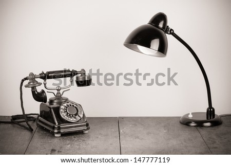 Vintage telephone and old desk lamp on table