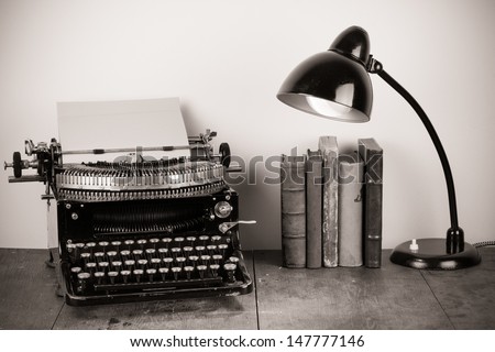 Vintage old typewriter, old books and retro lamp on table