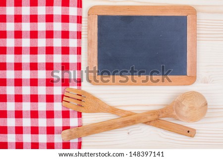 Black chalk board, tablecloth, kitchen equipment on wood background