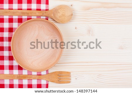 Tablecloth, wooden plate, spoon, fork on wood table background