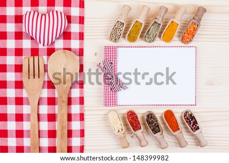 Spices in scoops, recipe cook book, spoon, fork, tablecloth, heart on wood background
