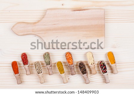 Spices in scoops, cooking cutting board on wood table background