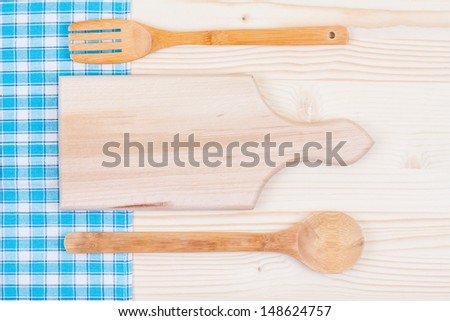 Tablecloth, empty kitchen cutting board, fork, spoon on wooden table background