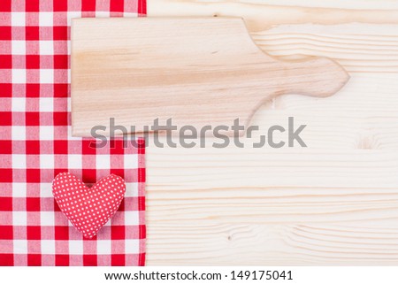 Red tablecloth, cook plank and love heart on wooden table background
