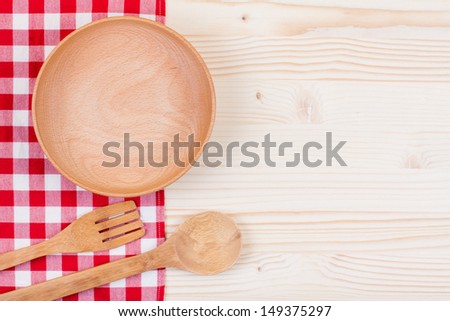 Wooden plate, tablecloth, spoon, fork on wood table background