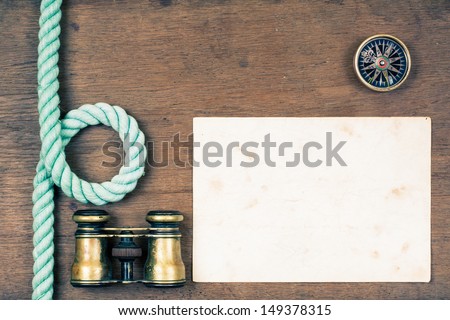 Vintage binoculars, compass, old map blank, rope on wooden texture background