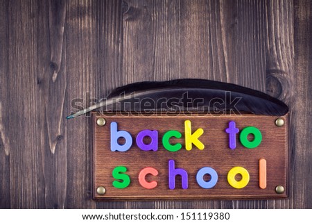 Back to school sign board of color letters, quill pen on wooden background