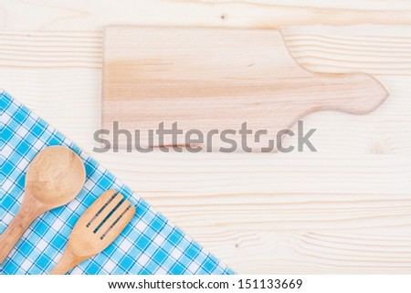Tablecloth, empty kitchen board, fork, spoon on wooden table background
