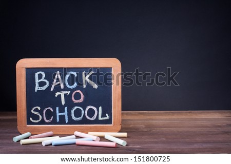 Back to School on a blackboard, chalk on desk in front black background