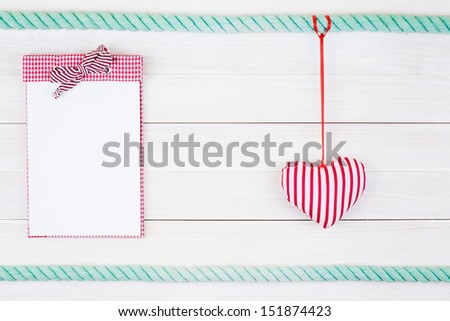 Notebook and heart hang on white wood wall background