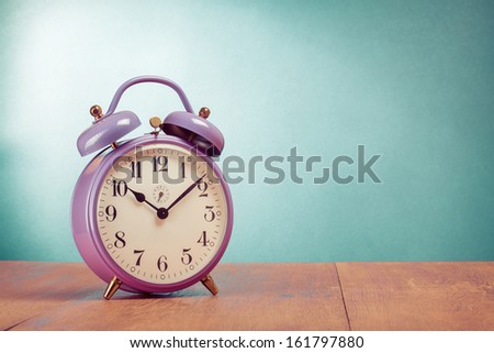 Retro alarm clock on table front mint green background