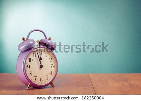 Retro violet alarm clock on desk front mint green wall background