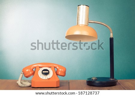 Retro telephone and desk lamp on table