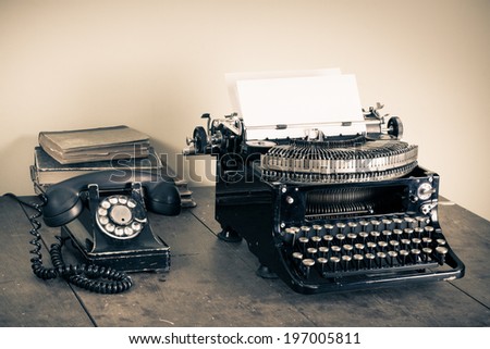 Vintage telephone, old typewriter, books on table