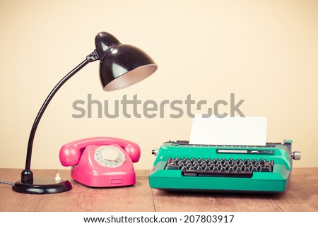 Retro typewriter with paper, old desk lamp, rotary telephone on table