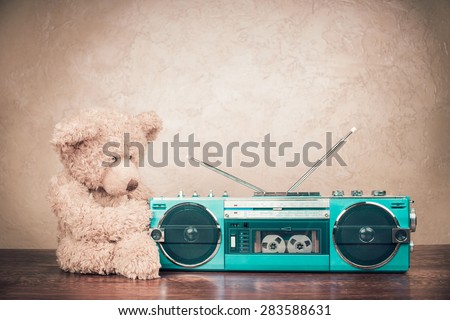 Retro mint green radio cassette recorder from 80s, and old Teddy Bear toy on table. Vintage instagram style filtered conceptual photo