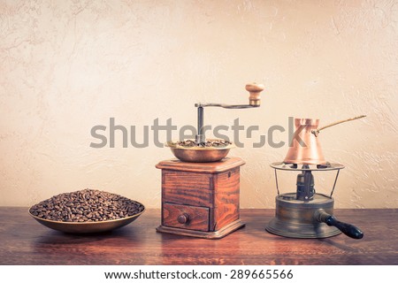 Retro coffee grinder with beans, coffee pot on old kerosene cooking stove. Vintage instagram style filtered photo