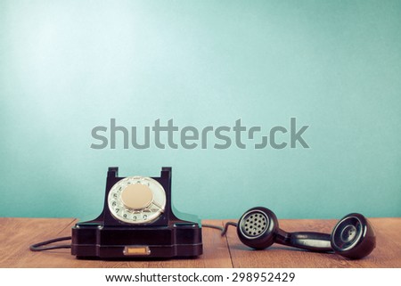 Retro rotary telephone on table in front mint green background. Old instagram style filtered photo